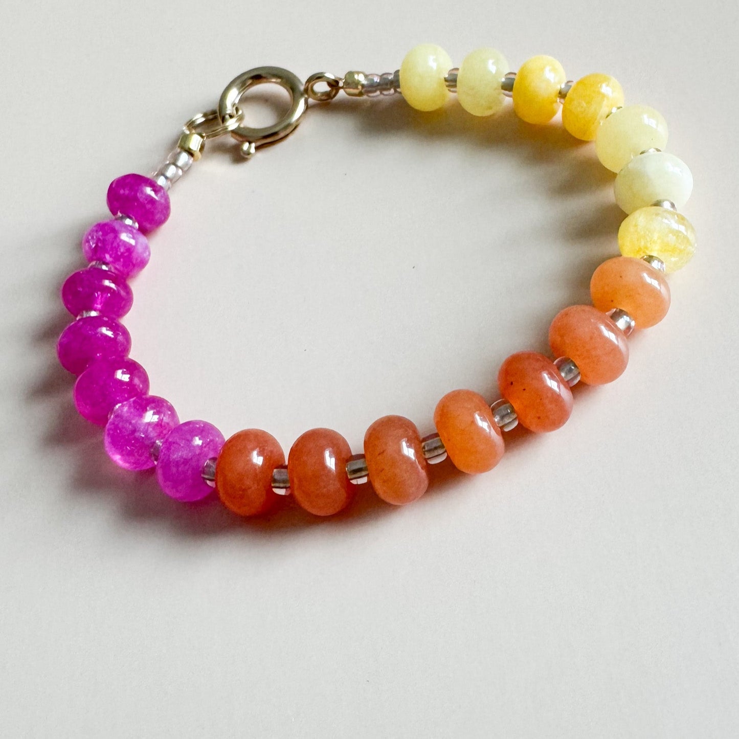 Pink, orange, and yellow abicus beaded bracelet on a light gray background.