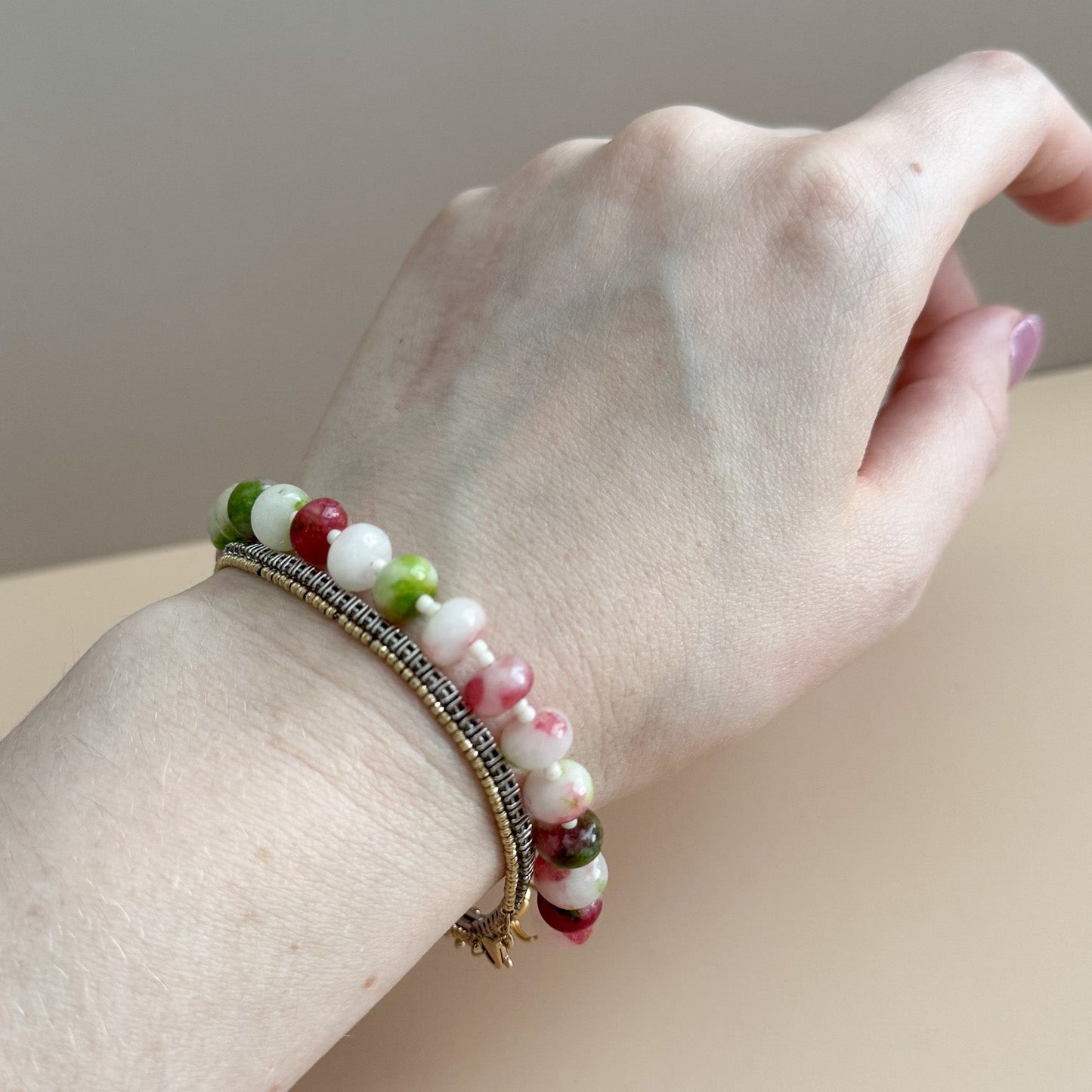 Hand wearing a bracelet with multicolored beads on a neutral background