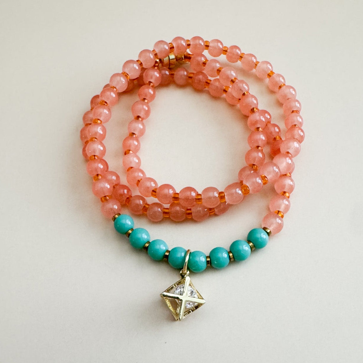 Necklace with translucent orange and mint green beads on a light gray background