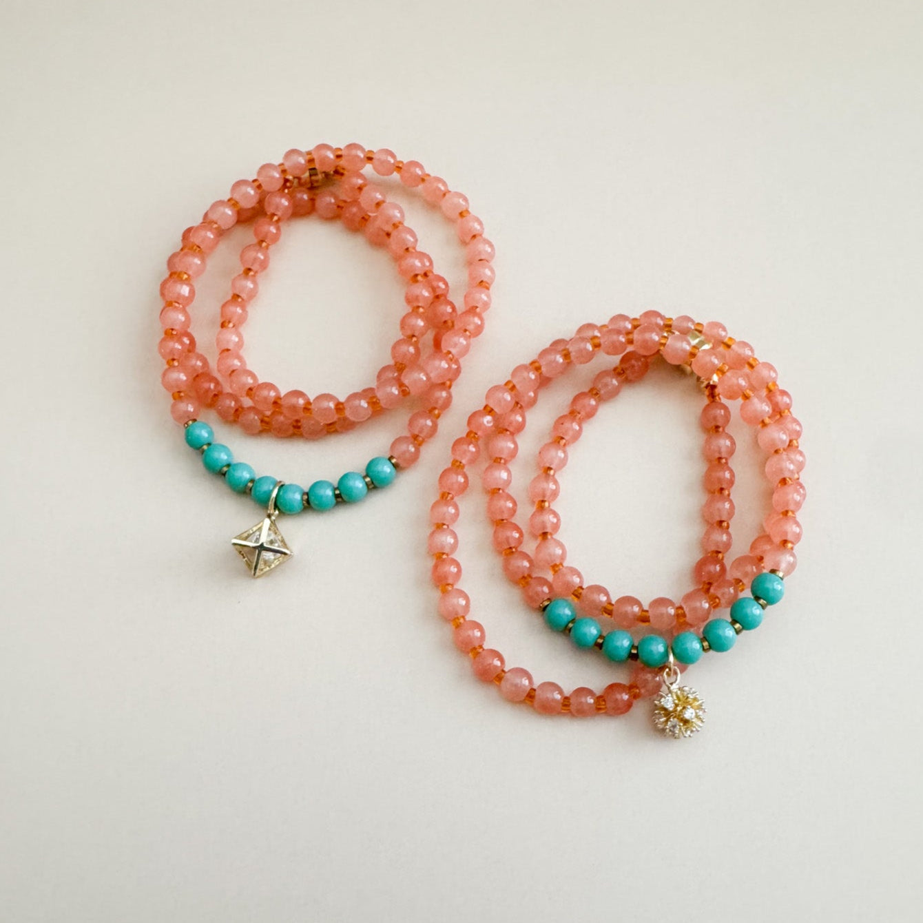 Two beaded bracelets with translucent orange and mint green beads and star charms on a light background