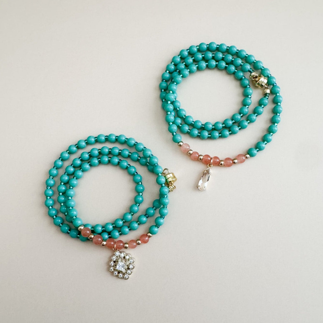 Two mint green and translucent orange beaded bracelets with gold accents on a light gray background