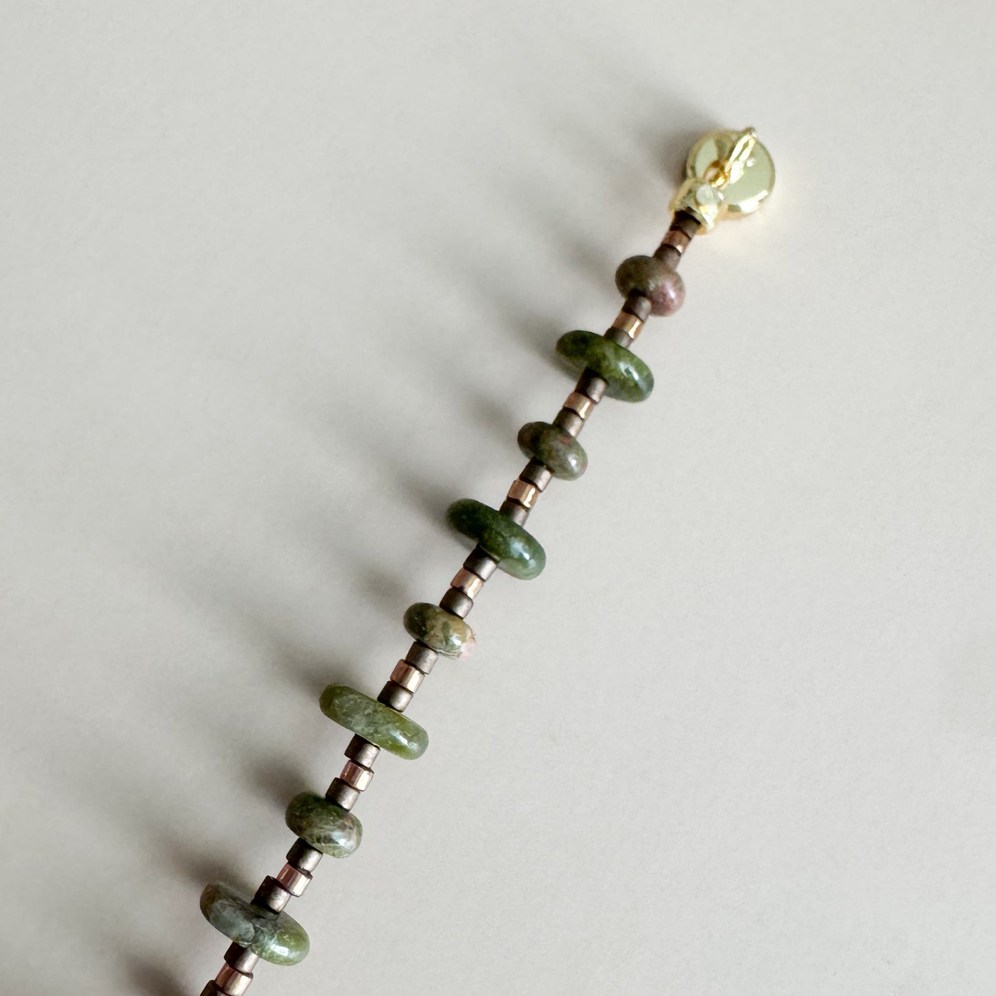 Beaded bracelet with unakite beads and a gold magnetic clasp on a light gray background