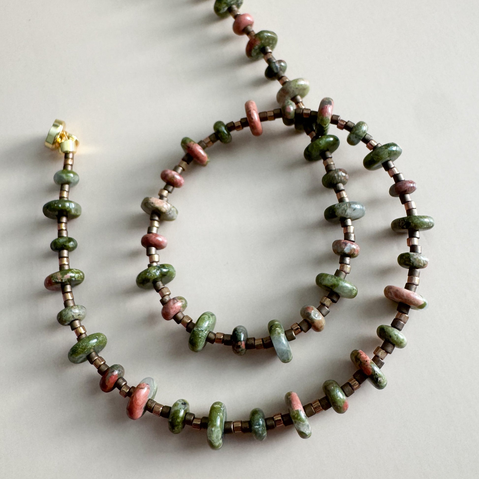 Necklace with unakite beads on a light gray background
