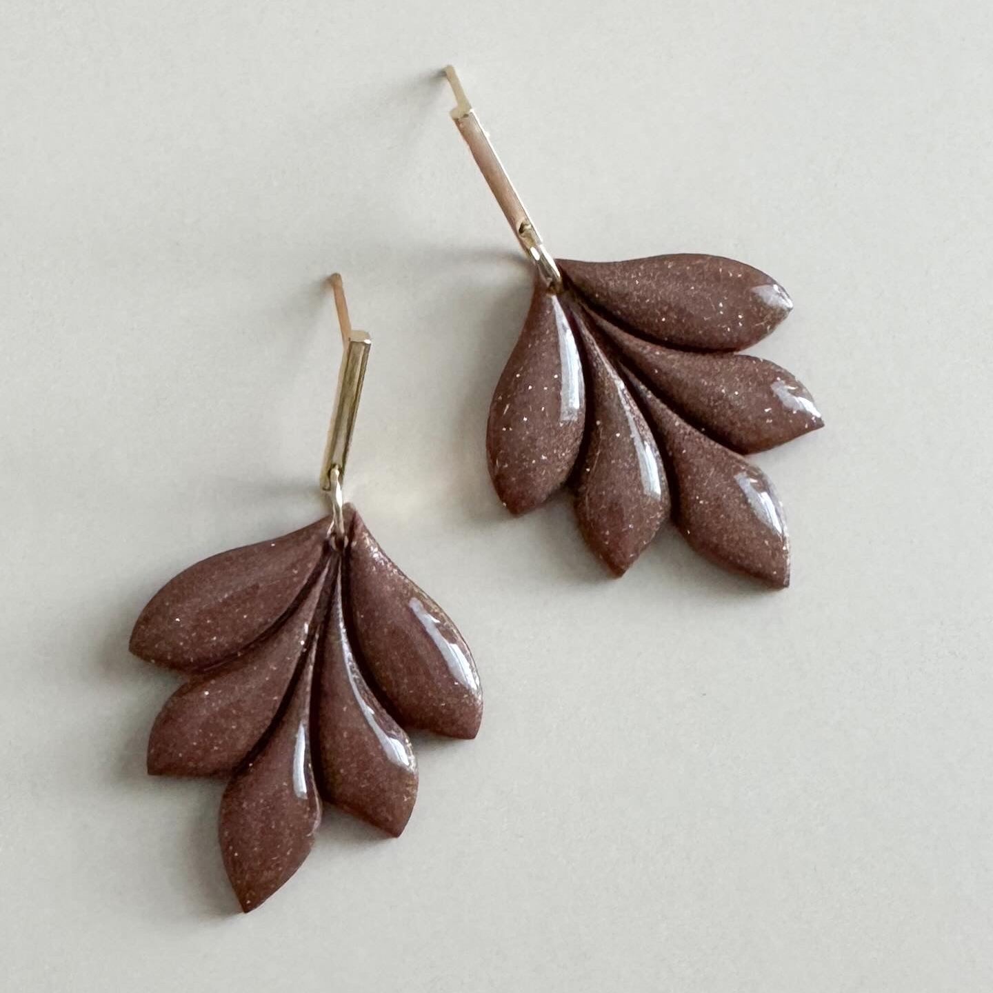 Pair of light brown leaf-shaped earrings on a light gray background