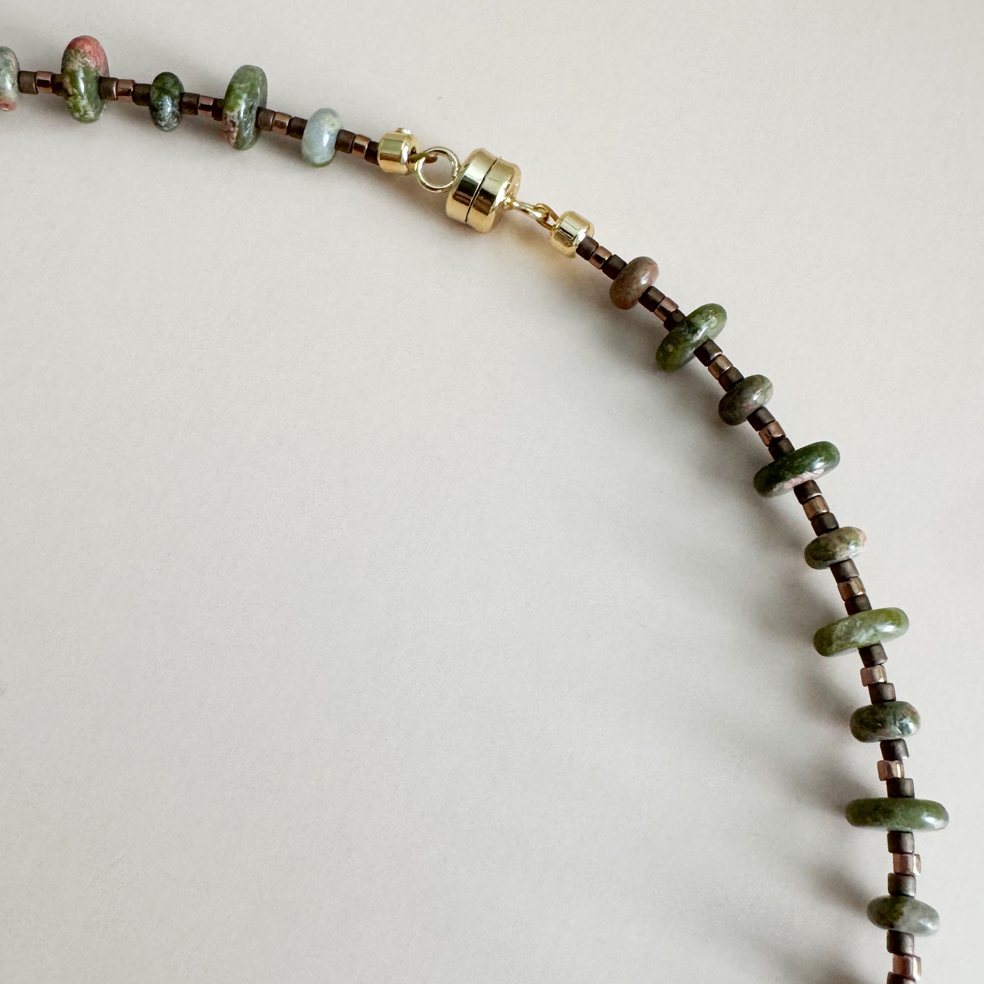 Necklace with unakite beads, highlighting gold magnetic clasp on a light gray background