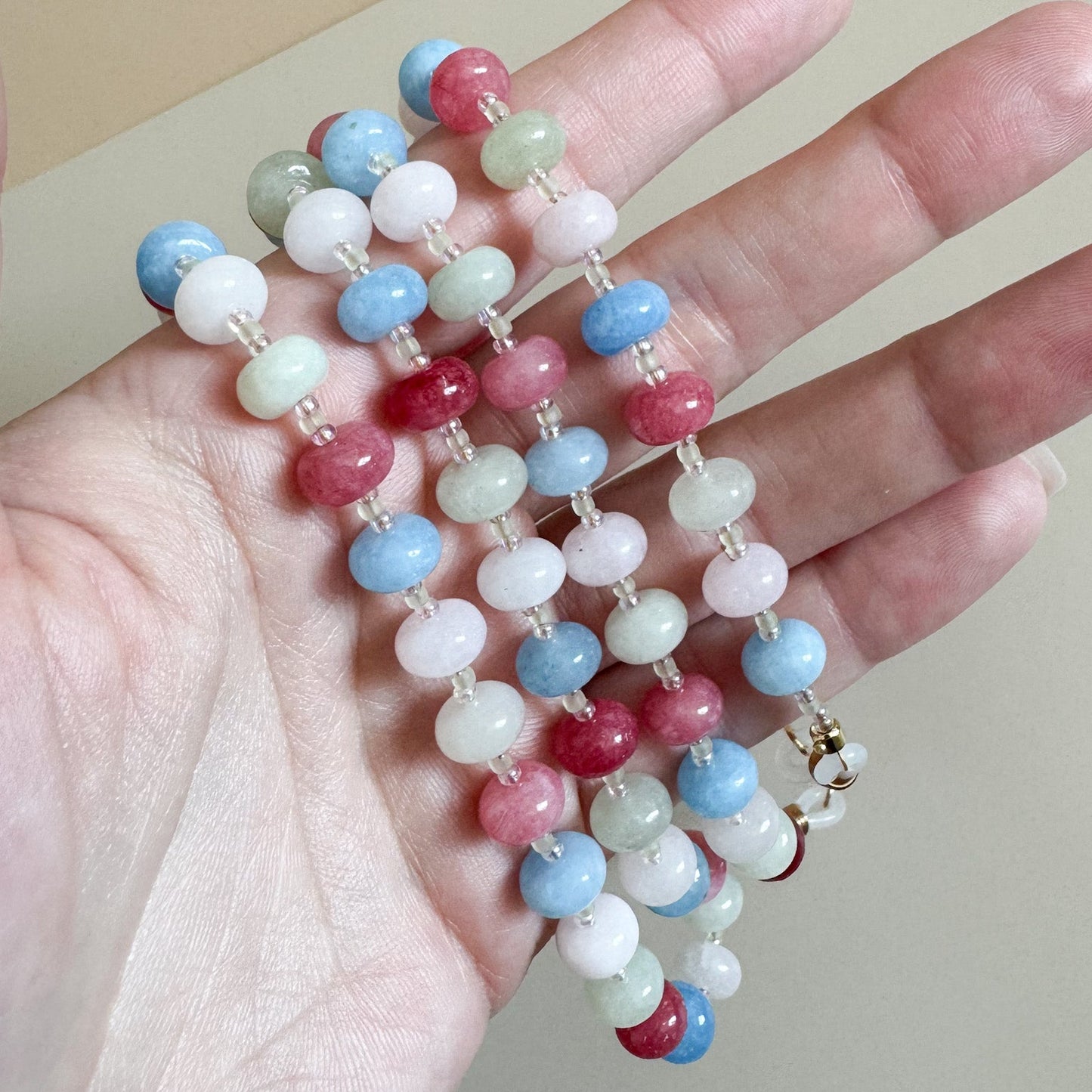 Colorful beaded lanyard held in a hand against a neutral background