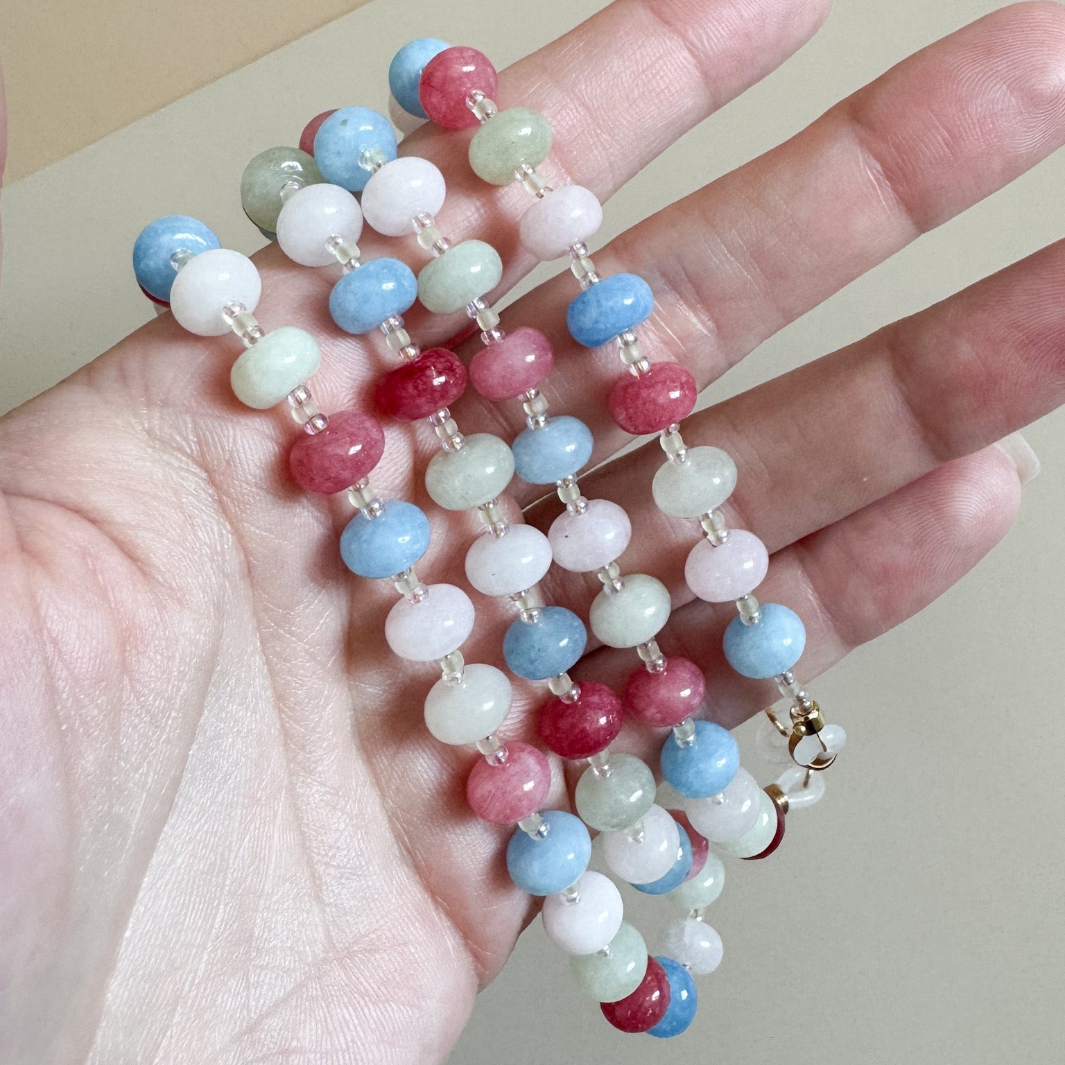 Colorful beaded lanyard held in a hand against a neutral background