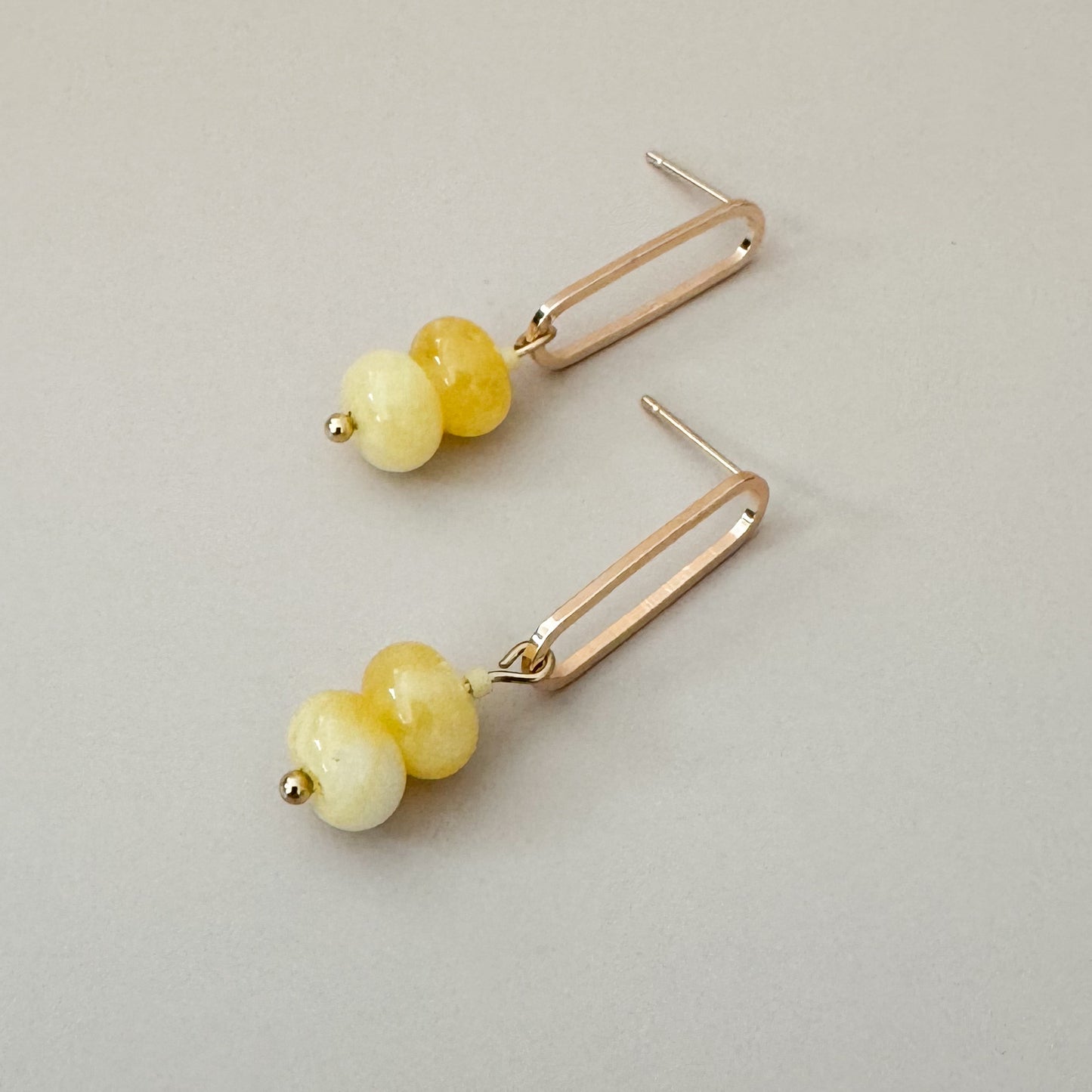 two butter yellow beads complemented with a monochrome seed bead attached to a golden oval earring