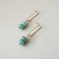 two seafoam beads complemented with a pale pink bead attached to a golden oval earring