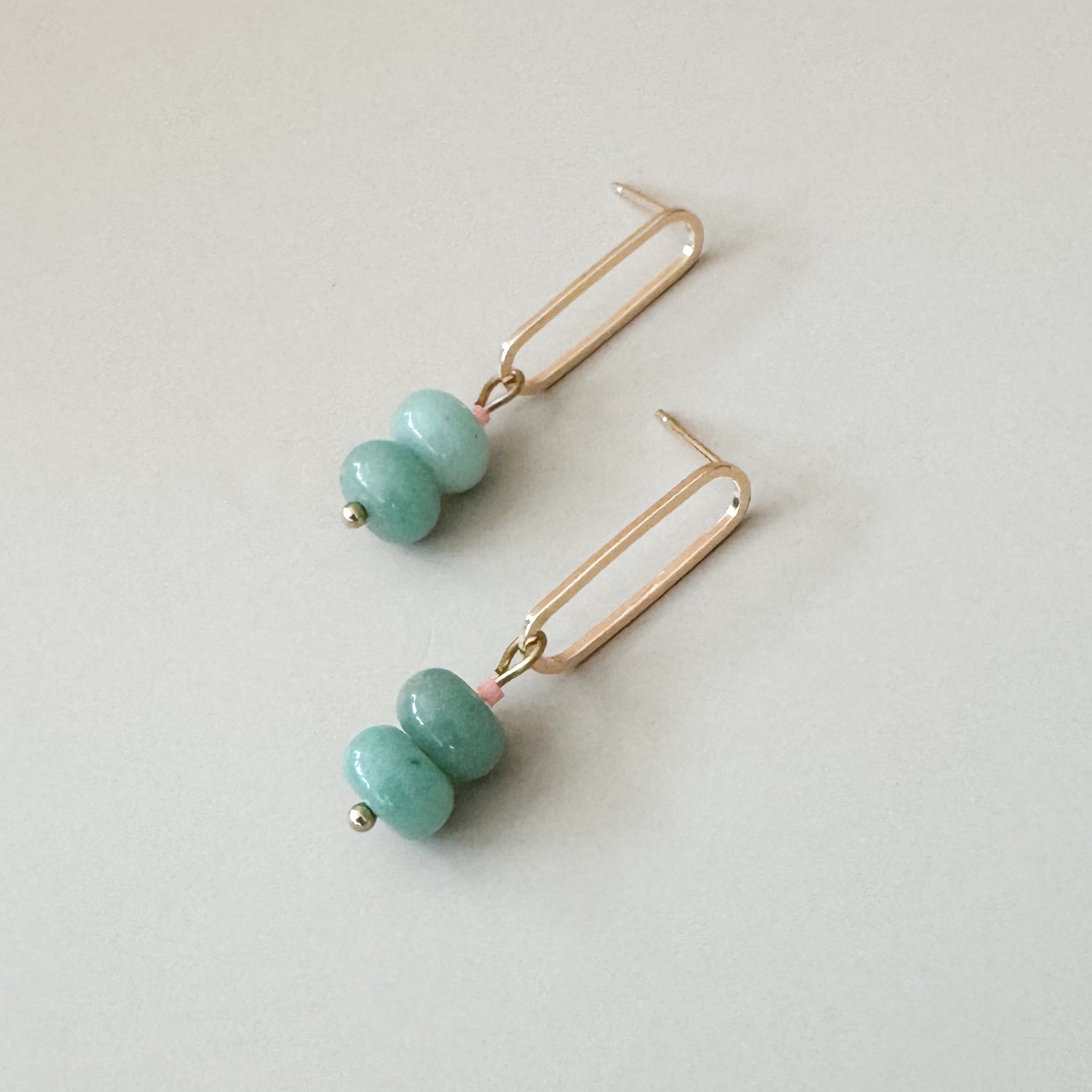 two seafoam beads complemented with a pale pink bead attached to a golden oval earring