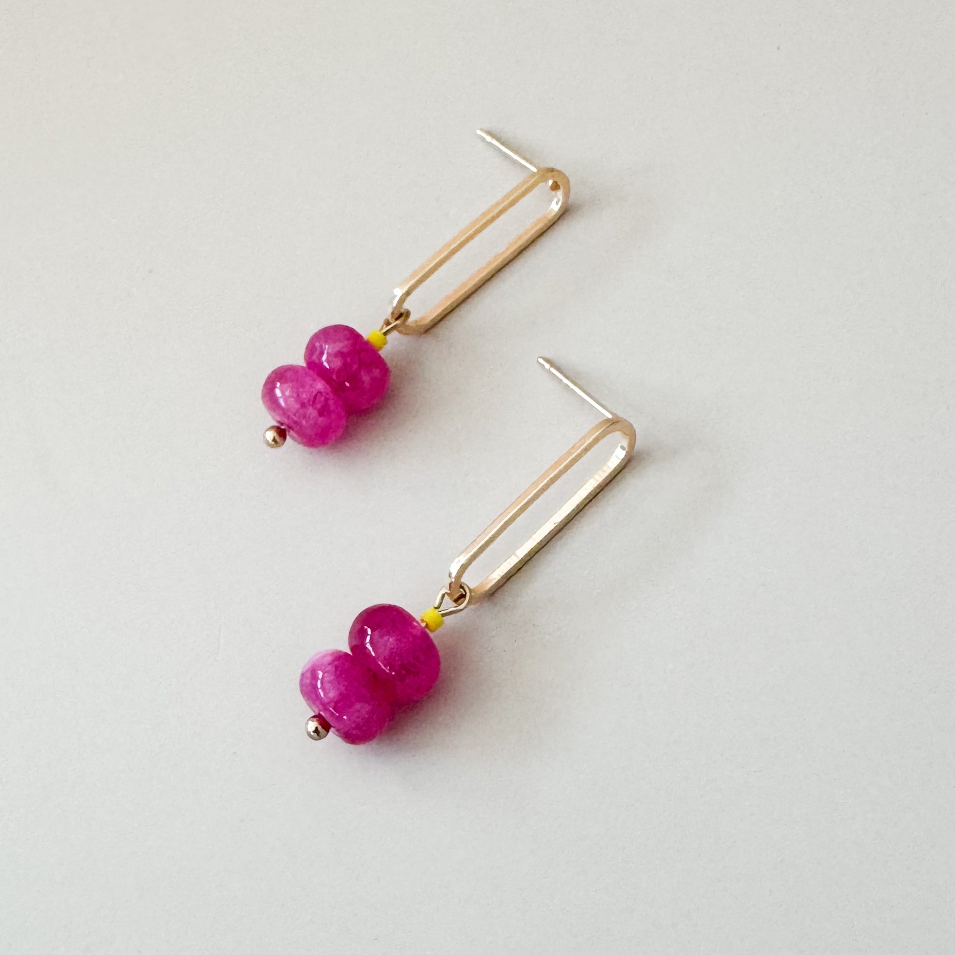 two pink beads complemented with a neon yellow attached to a golden oval earring