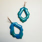 Pair of blue and green sparkling earrings on a light gray background
