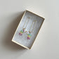 Colorful beaded earrings in a jewelry box on a light gray background