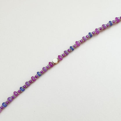 Beaded bracelet with purple and blue beads on a light gray background