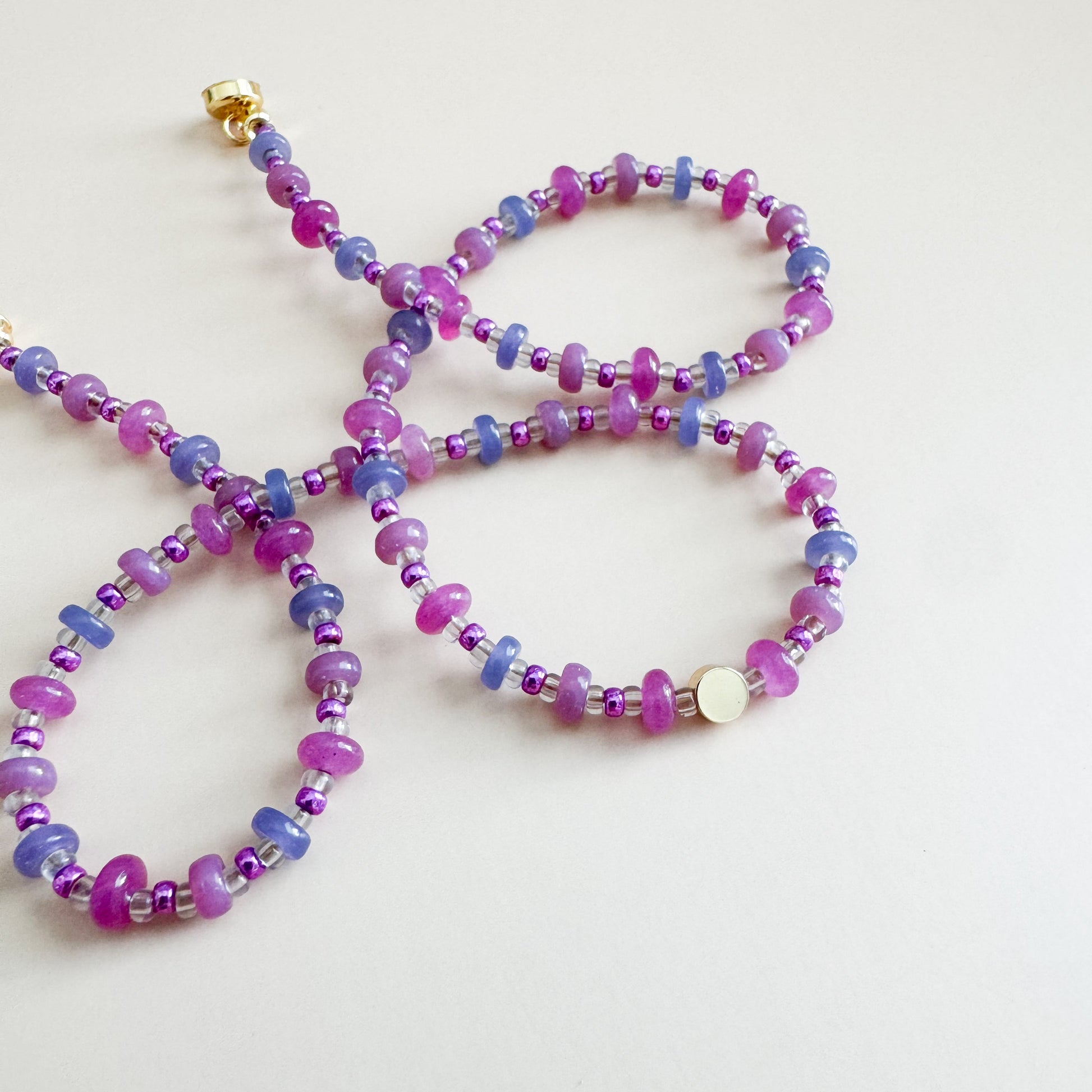 Beaded necklace with pink and purple beads on a light gray background
