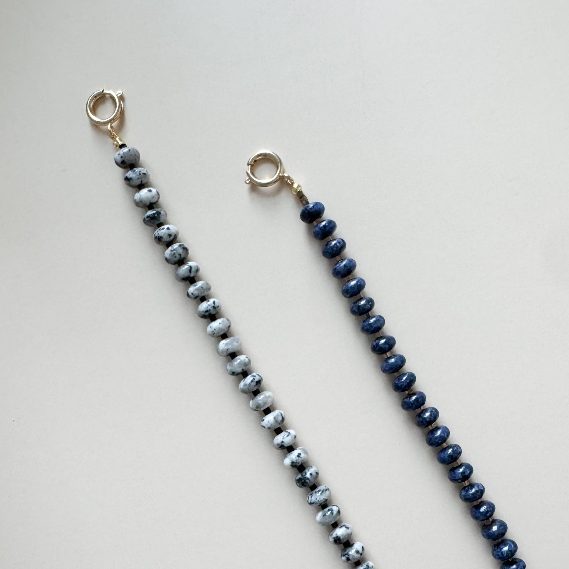 Two beaded lanyards, one blue and one gray, on a light gray background.