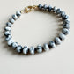 Bracelet with white, gray, and black speckled beads on a beige background