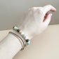 Hand wearing a bracelet with beads on a neutral background