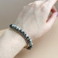 Hand wearing a bracelet with a neutral background