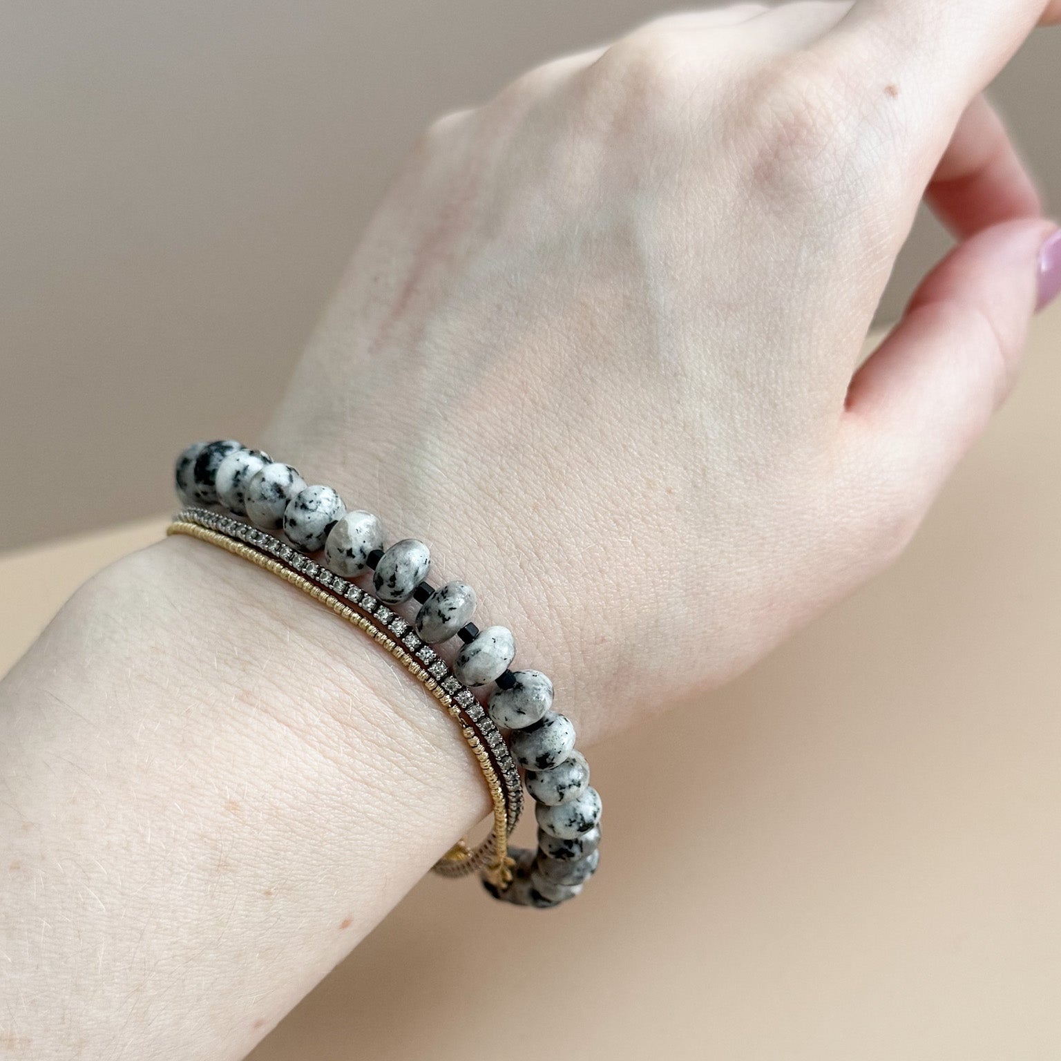 Hand wearing a bracelet with a neutral background