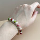 Hand wearing a bracelet with multicolored beads on a neutral background