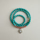 mint green and translucent orange beaded necklace with a decorative pendant on a light gray background