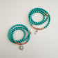 Two mint green and translucent orange beaded bracelets with gold accents on a light gray background