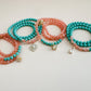Set of mint green and translucent orange beaded bracelets with star-shaped charms on a light gray background