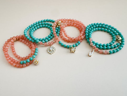 Set of mint green and translucent orange beaded bracelets with star-shaped charms on a light gray background